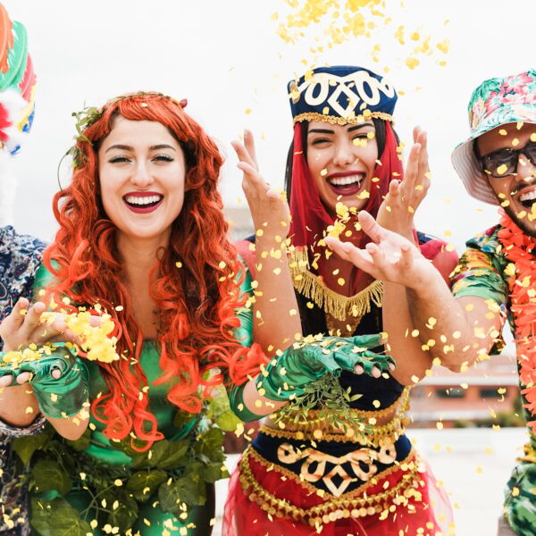 Happy dressed people celebrating at carnival party throwing confetti